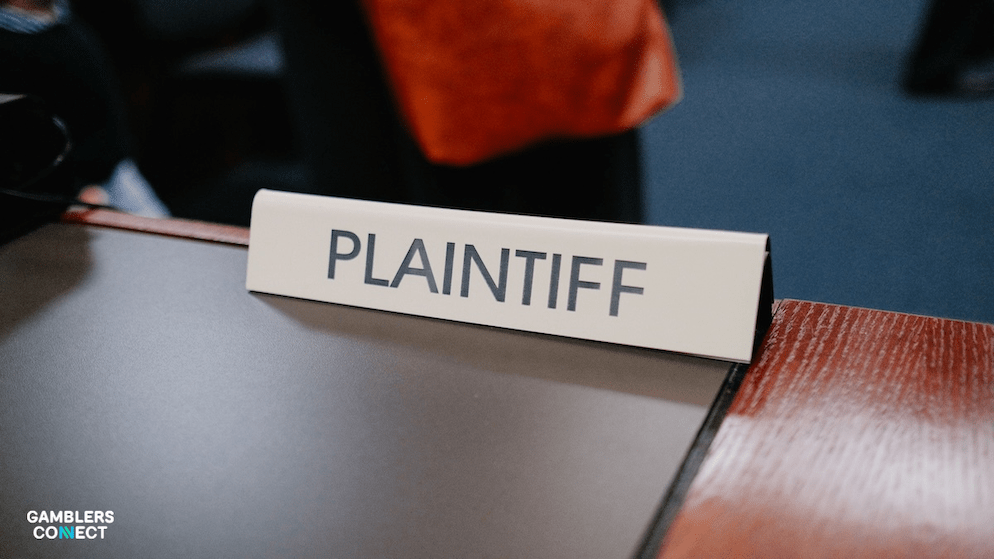 A 'Plaintiff' nameplate on a desk, illustrating the legal investigation by India's Enforcement Directorate into Google over illegal betting ads.