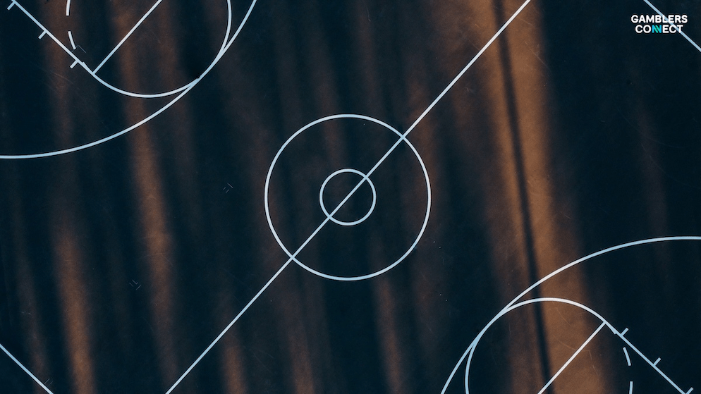 A dark, modern graphic of a basketball court's center circle, illustrating the new legal framework for basketball betting proposed by Hong Kong's Home and Youth Affairs Bureau.