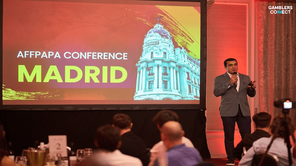 A speaker presenting at a conference in Madrid, with a backdrop featuring a landmark building, showcasing the city's capacity to host significant iGaming gatherings like the relocated iGaming Club Conference.