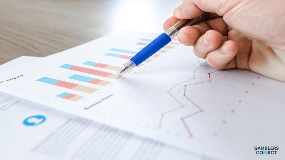 A close-up of a hand with a pen pointing to a bar chart on a financial performance document, illustrating the analysis of quarterly results in the gaming industry.