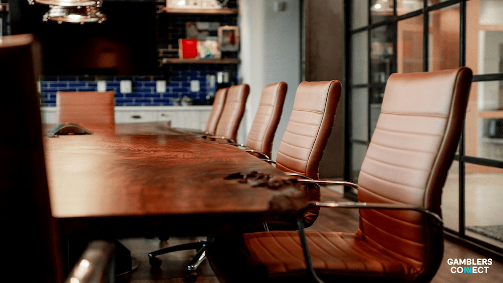 A modern, upscale conference room with a long wooden table and brown leather chairs, designed for strategic discussions and meetings of an advisory board.