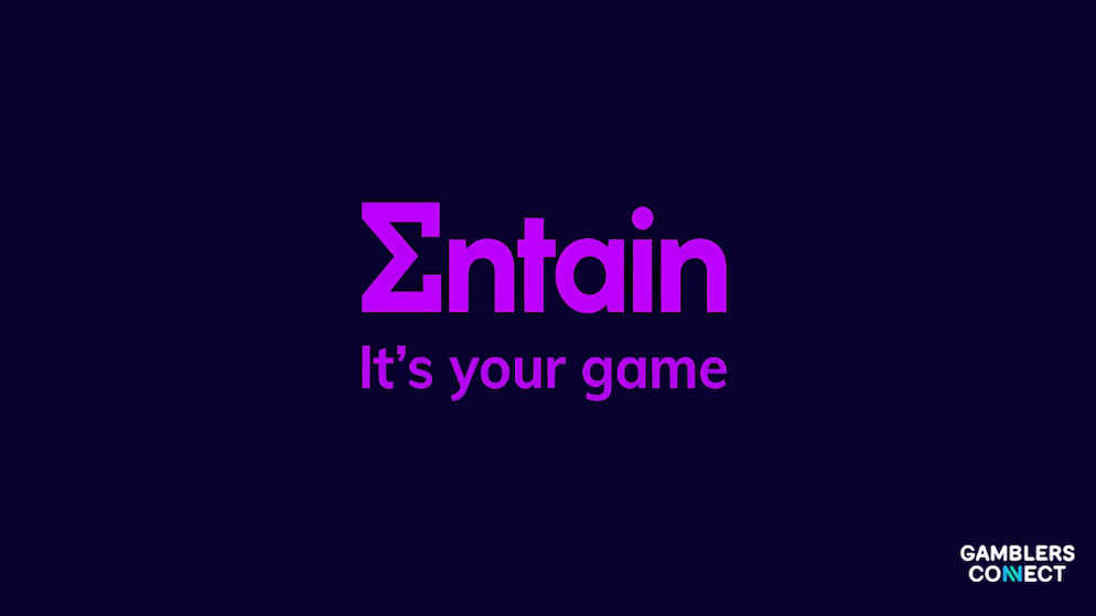 The Entain logo and tagline ("It's your game") in purple hues against a deep blue backdrop, representing the corporate identity of the global gaming operator that announced its H1 2025 results.
