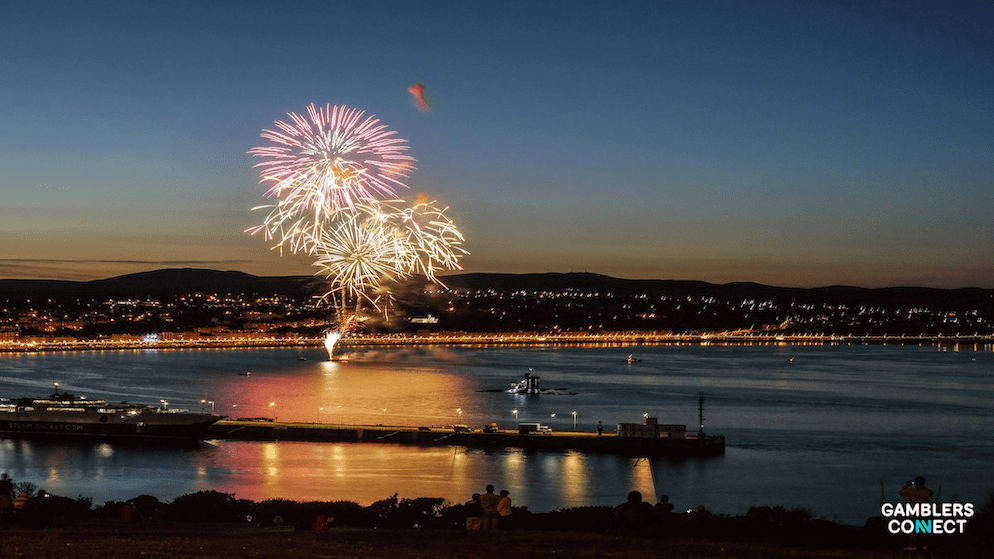 Nighttime scene with fireworks reflecting on water, representing the Isle of Man and the strategic realignment of Annexio's licensing framework.