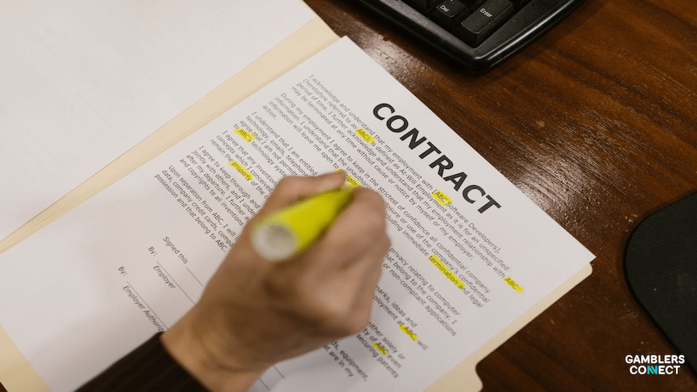A close-up of a legal contract with the prominent heading "CONTRACT," partially visible amongst other documents, suggesting the complex legal agreements involved in the PointsBet acquisition battle between Betr and Mixi. A hand holding a yellow highlighter marks a specific section, indicating review or emphasis on particular clauses within the agreement.