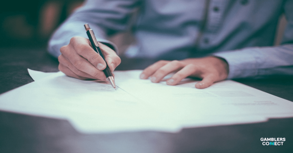 Hands holding a pen over a document, illustrating the decision-making process for Ainsworth shareholders regarding the Novomatic takeover.