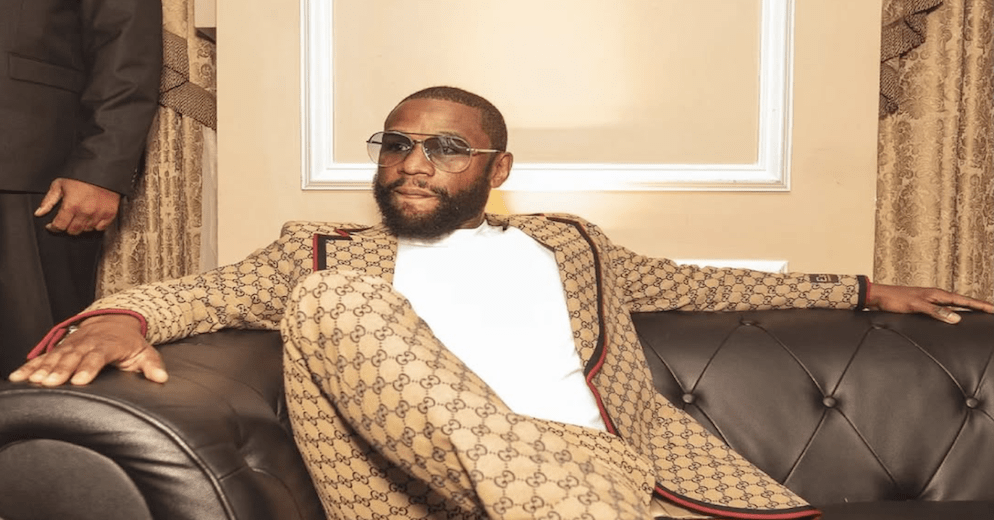 Floyd Mayweather Jr. confidently posing in a luxurious designer suit and sunglasses, reflecting his extravagant personal style and the lavish lifestyle afforded by his considerable Floyd Mayweather net worth.