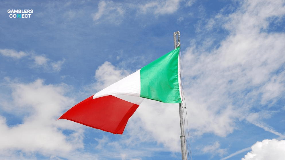The flag of Italy flying against a bright blue sky with scattered clouds, symbolizing the nation's significant overhaul of its online gambling framework.