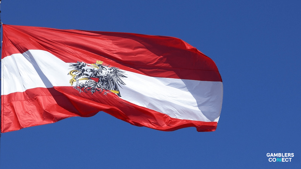 The Austrian flag, featuring a red-white-red horizontal triband with the national coat of arms, waving against a clear blue sky, symbolizing the country's potential gambling market reform.