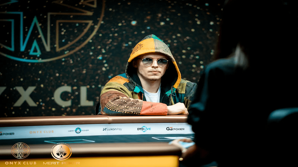 A photo of Ossi Ketola, aka The Monarch, wearing a multi-colored hoodie and sunglasses while playing in a high-stakes poker tournament.