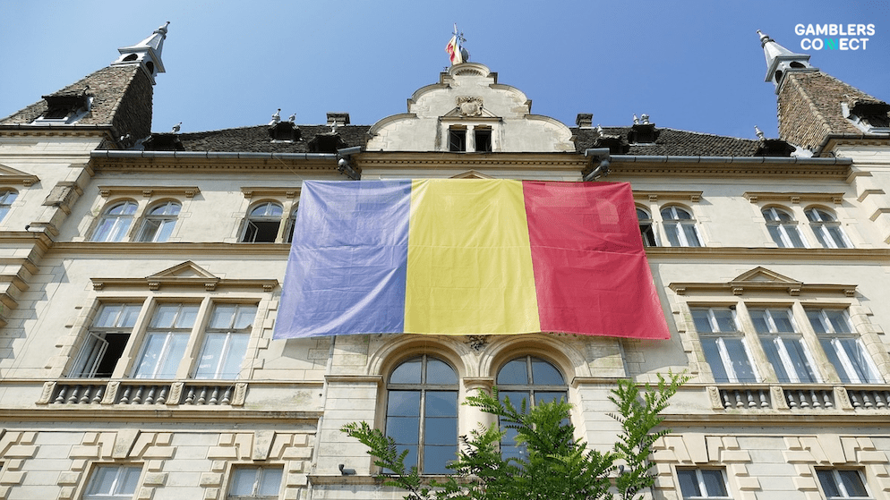 The flag of Romania prominently displayed on the facade of a historical building, representing the country's regulatory authorities.