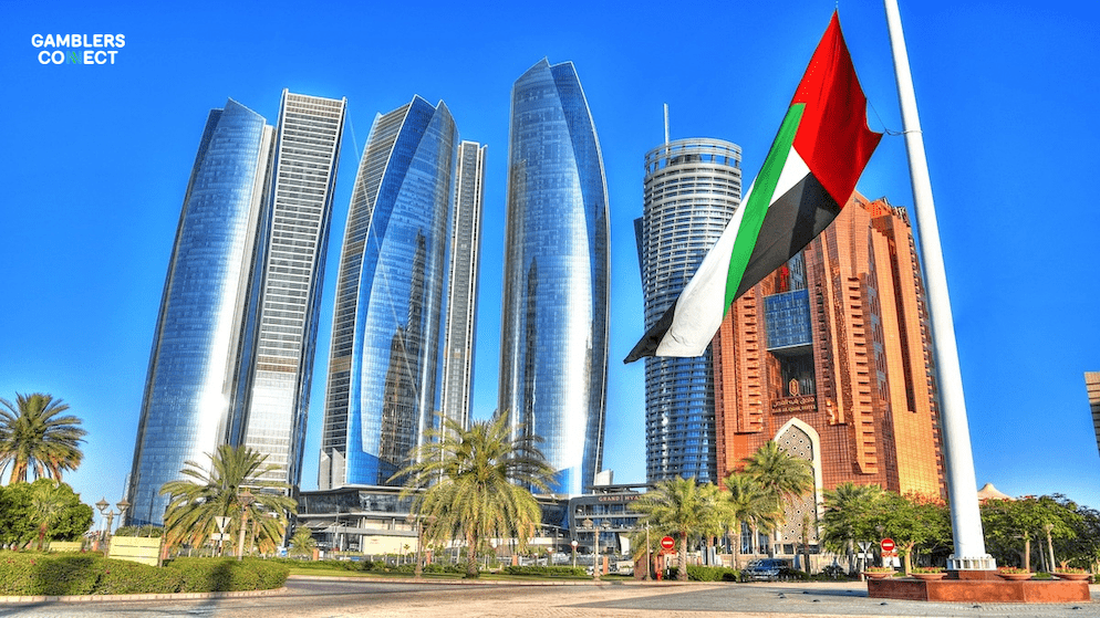 A wide shot of the Abu Dhabi financial district with the UAE flag, symbolizing the country's transition to a regulated online gaming market and its vision to be a global innovation hub, GCGRA B2C.