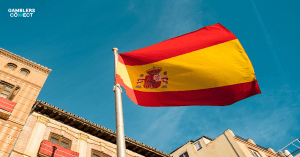 Vibrant Spanish flag waving against a clear sky, symbolizing UNAD's call for a nationwide ban on gambling advertising in Spain.