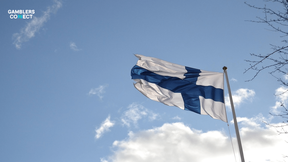 The Finnish flag against a clear sky, signifying the country where Veikkaus operates and is currently under scrutiny for its marketing practices.