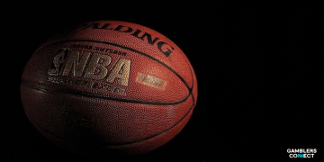 A stark, dimly lit NBA basketball on a dark background, powerfully symbolizing the integrity of the league under the shadow of a serious gambling investigation.