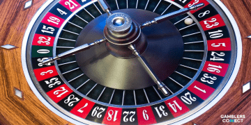 A top-down close-up of a wooden roulette wheel with the ball landing on red 23, symbolizing the fairness and integrity guaranteed by US casino regulators.