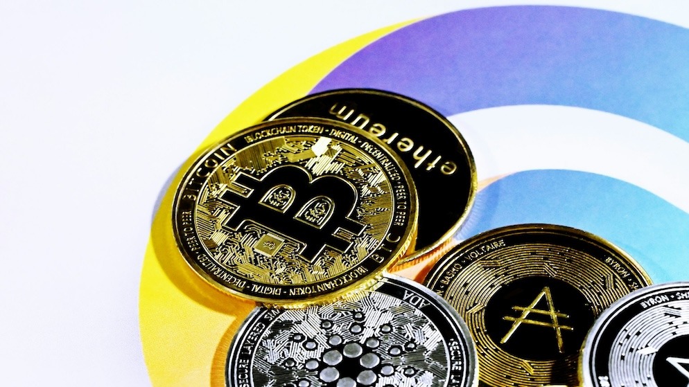 A gold-colored physical bitcoin coin resting on a pile of US one-hundred dollar bills, symbolizing the financial motives behind a "bundle buy" or "sniping" strategy in a token launch.