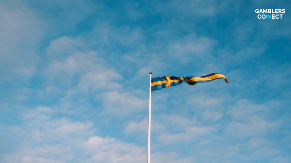 A flag of Sweden waving on a flagpole, representing the government's renewed focus on controlling the gambling sector with Erik Eldhagen appointment.