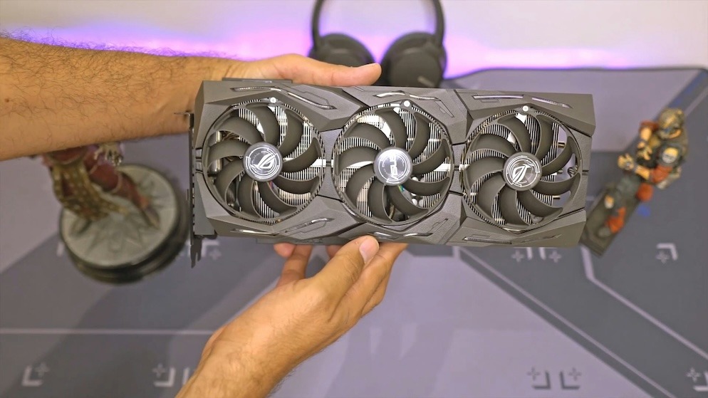 A miner holding a large triple-fan graphics card, demonstrating the hardware needed when learning how to mine dogecoin on PC versus using cloud solutions.