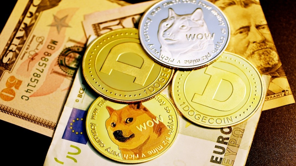 A high-quality photo of physical gold and silver Dogecoin cryptocurrency coins resting on a pile of US Dollar and Euro banknotes.