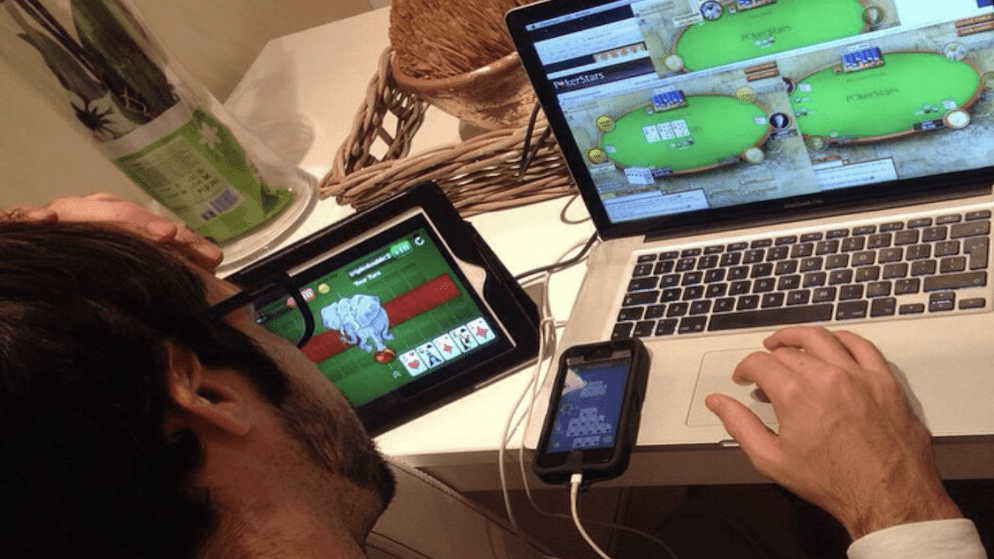 A person (representing Jason Mercier's online persona) multi-tabling online poker across a laptop, tablet, and smartphone.