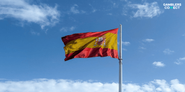 Flag of Spain waving against a blue sky, symbolizing the new national regulatory measures passed at the International Gaming Congress.