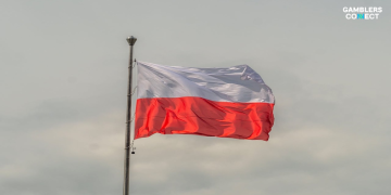 Polish President Karol Nawrocki signing a document at a desk with the Polish flag visible, symbolizing the presidential veto.