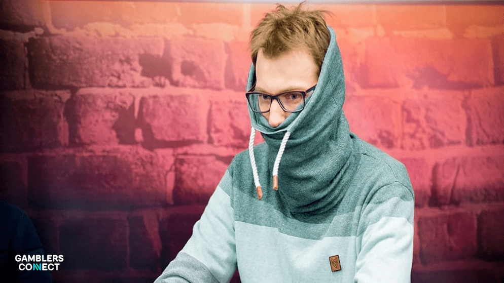 A close-up of Christoph Vogelsang's face almost entirely obscured by his clothing, demonstrating his extreme measures to maintain an unreadable poker face against elite competition.
