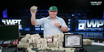 Dan Harrington, wearing his signature green cap, smiling and holding up his winning cards and a stack of cash after winning a World Poker Tour (WPT) event.