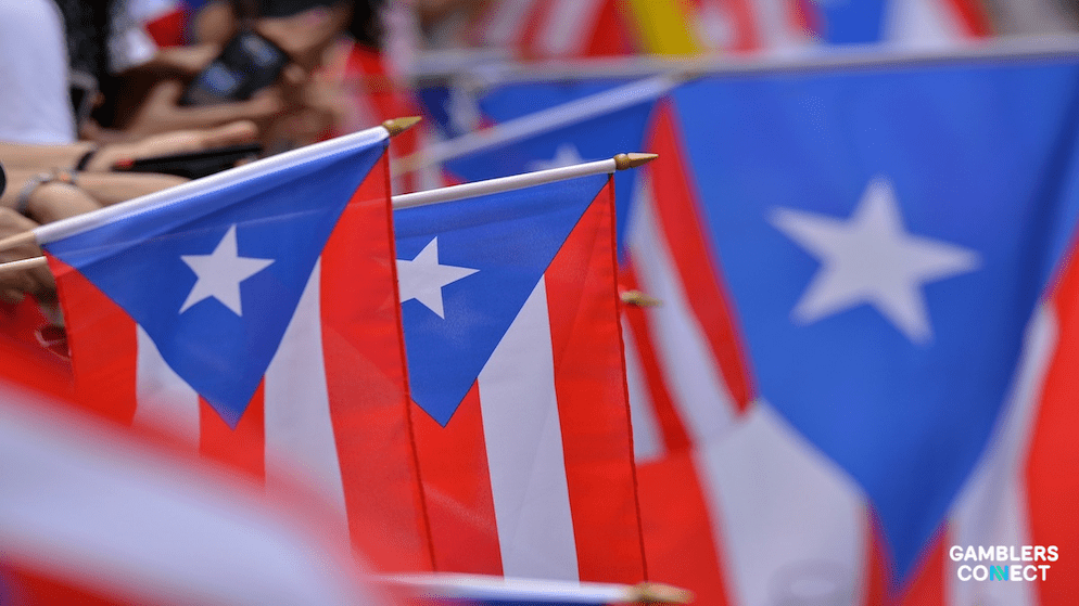 A person holding a smartphone displaying the official Lotería Móvil PR interface, representing the shift from physical retailers to digital play.