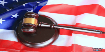 A wooden judge's gavel resting on an American flag, symbolizing the legal action taken by Nevada regulators against Polymarket.