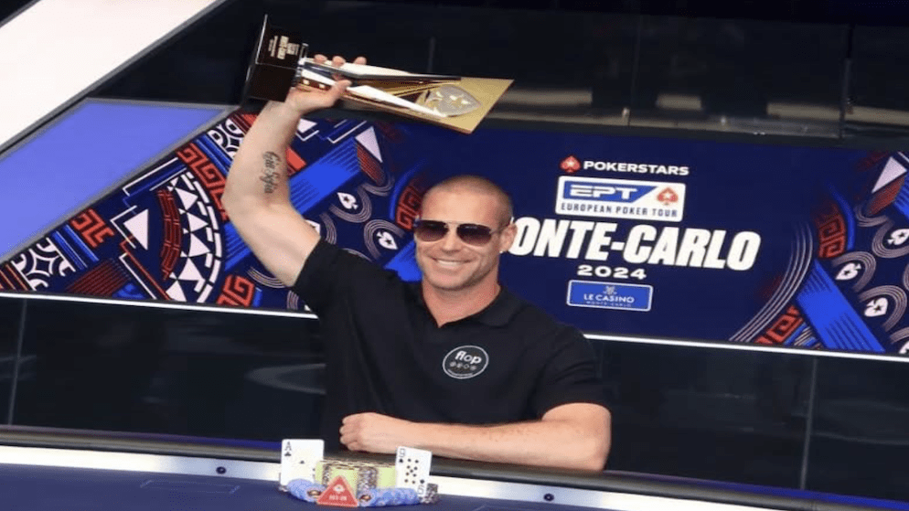 Patrik Antonius lifting a trophy at the EPT Monte Carlo 2024, wearing sunglasses and a black polo with the 'FLOP' logo, celebrating another major high-roller title.