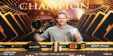 Patrik Antonius smiling and holding the golden Triton Poker Series trophy and his winning hand of Queen-Jack suited after winning the $200,000 Invitational.