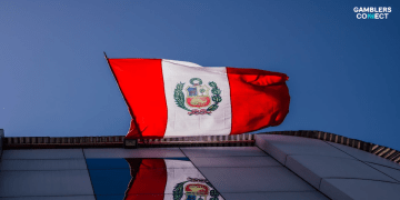 A low-angle shot of the Peruvian flag waving against a deep blue sky, symbolizing the country's leading position in betting intentions for the 2026 World Cup.