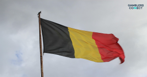 The national flag of Belgium waving under a cloudy sky, representing the new regulatory standards for the country's iGaming sector.