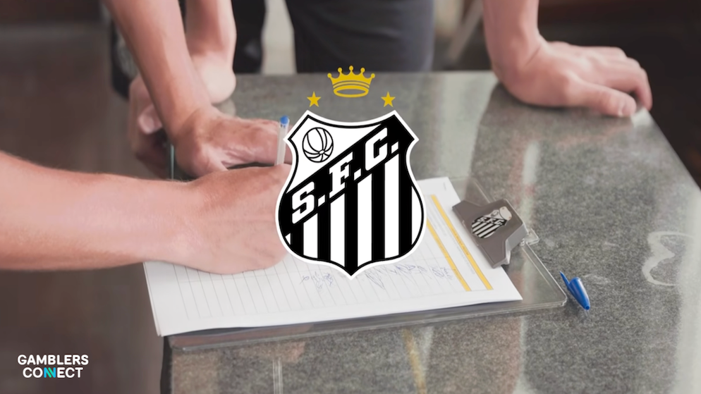 Hands signing an official document with the Santos FC crest in the center of the frame.