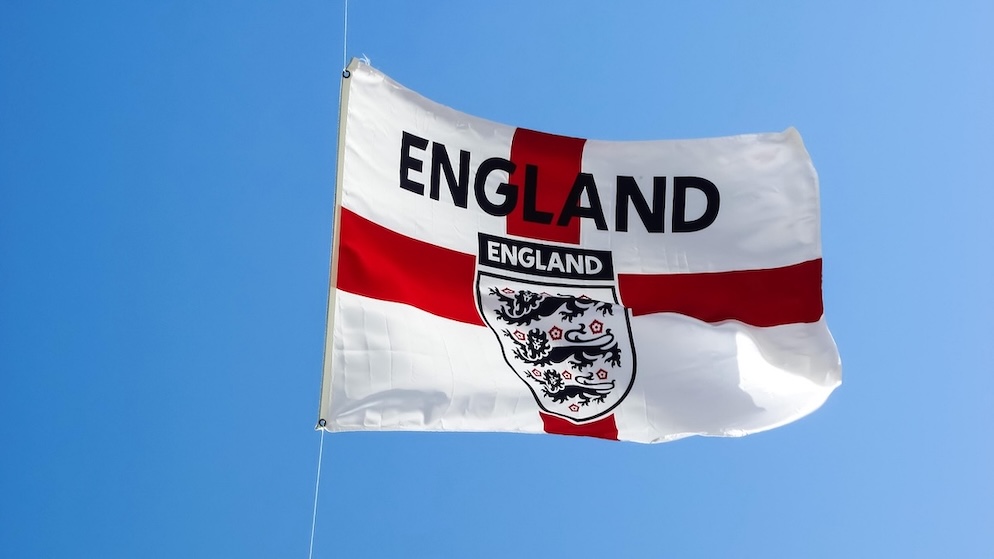 A bright England flag against a clear blue sky, representing the high expectations for Thomas Tuchel's squad in the USA, Canada, and Mexico.