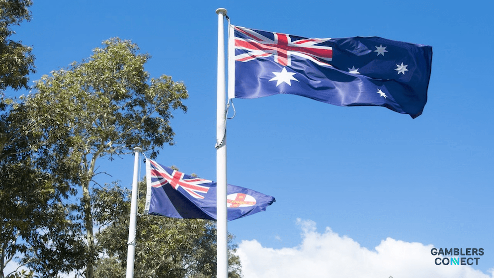 he Australian and United States flags flying together, representing the divergent regulatory philosophies regarding prediction markets such as Polymarket.