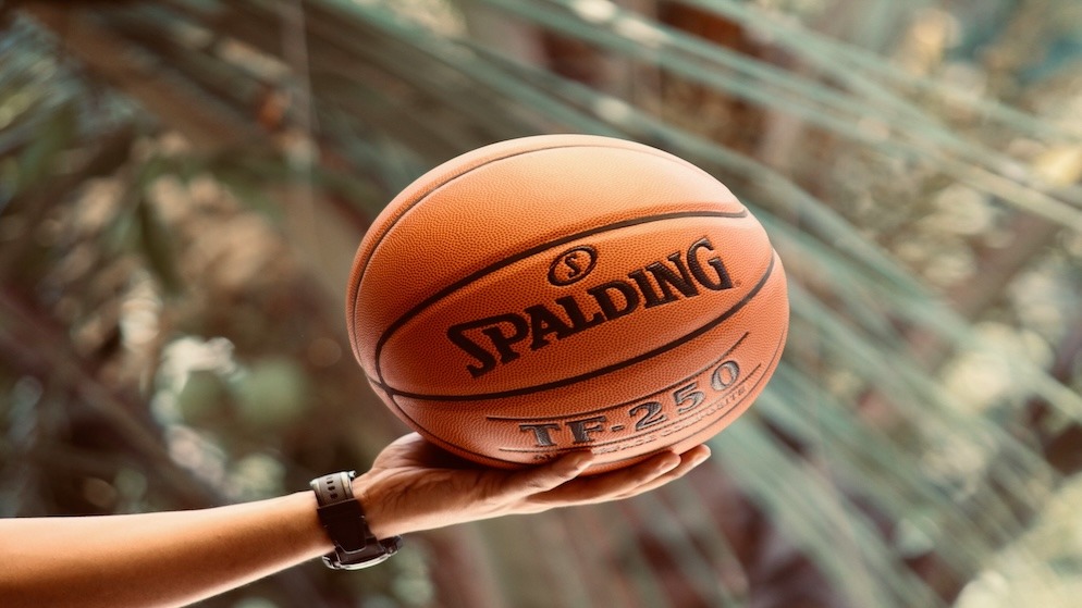 A person holding a Spalding NBA basketball TF-250 model, representing the brand that served as the official supplier for nearly four decades.