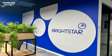 The Brightstar corporate logo on a vibrant blue office wall with white geometric circle designs and lush indoor greenery.