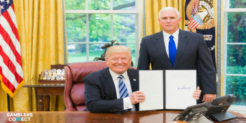 Donald Trump holding up a signed executive order in the Oval Office alongside Mike Pence.
