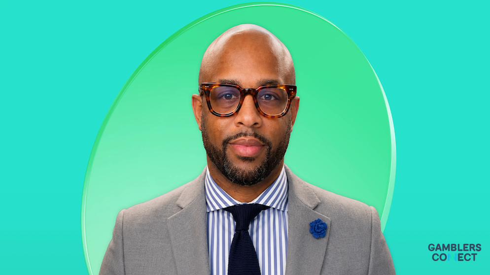 A clean corporate portrait of executive Khalid Reede Jones, framed within a light green circular border over a bright teal background layout.
