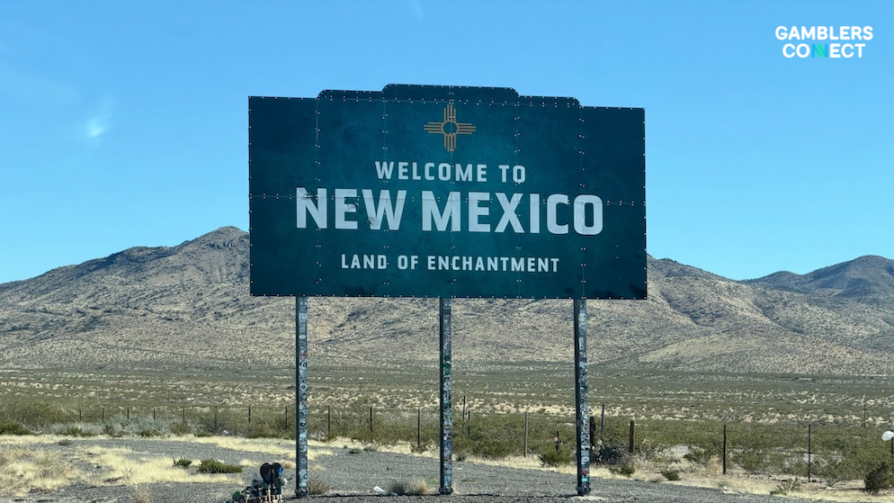 The prominent New Mexico welcome sign on a desert highway route, symbolizing the ongoing clash between state gaming laws and federal commodities oversight.