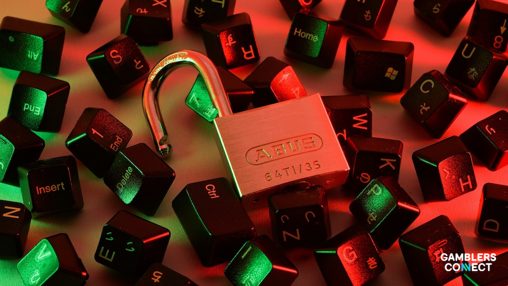 A close-up top-down view of a shiny steel padlock resting open on top of multiple black computer keyboard keycaps illuminated by ominous red and green neon lighting.