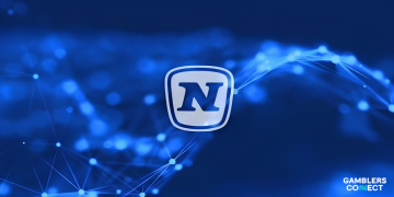 The official corporate logo of NOVOMATIC presenting its clean, stylized dark blue capital letter N enclosed within a rounded silver shield crest emblem, displayed on an abstract blue background.