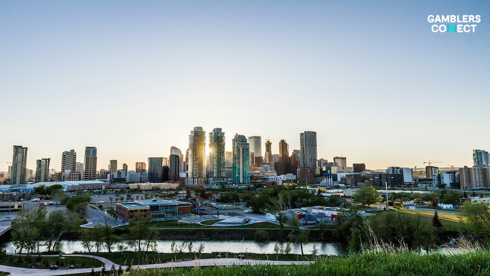 A high-angle panoramic view of the glass office buildings and urban high-rises defining the business district of an Alberta city at dawn.
