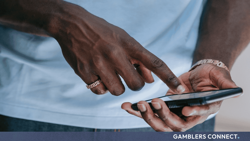 A close-up view of a user operating a mobile phone interface, illustrating the distribution of sponsored online betting links across digital networks.