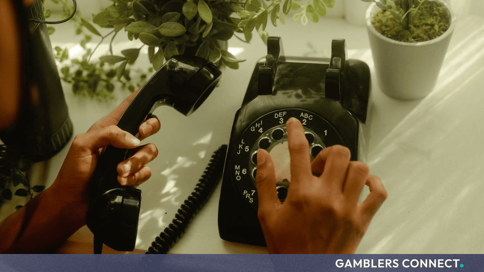 Close-up of a person dialing a vintage black rotary telephone, representing telecommunications customer service and consumer inquiries.