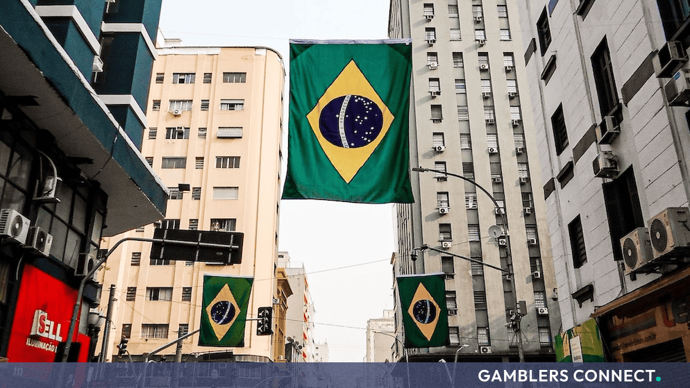 Brazil's Ministry of Finance Issues Strict Ordinance Targeting Unauthorized Prize Promotions and Commercial Lotteries 1 Looking up at the green and yellow Brazilian flag suspended between urban buildings on a clear day, symbolizing new regulatory updates in Latin America.