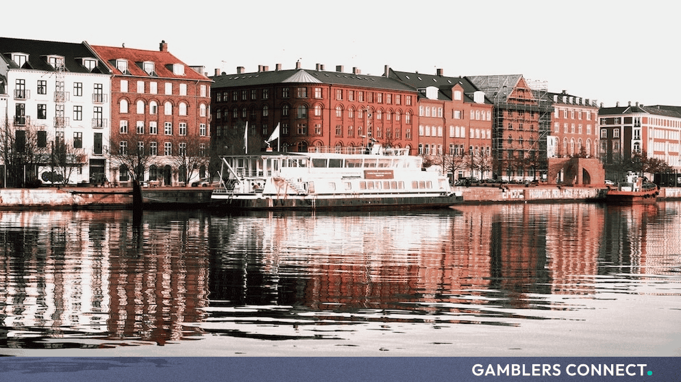 Classic red and white Scandinavian facades along a Danish canal, illustrating localized economic and regulatory trends within the Nordic market.