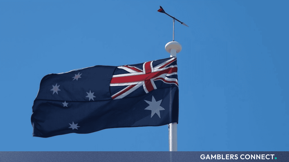 Close-up view of the Australian flag hoisted on a white pole under a vivid blue sky, highlighting shifting compliance frameworks within the Oceania iGaming market.